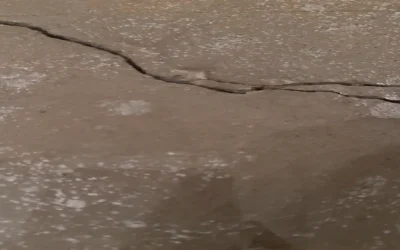 Close-up of a cracked concrete slab, showing separation and potential structural shifting — a possible sign of a slab leak or foundation movement beneath the surface. This type of damage often occurs when underground pipes leak and erode the soil supporting the slab.